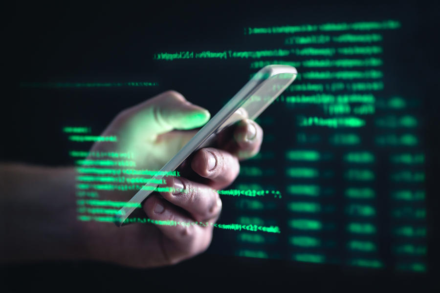 mão masculina segurando um celular e números binários em verde em volta
